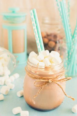 Sıcak kakao ve kokteyl kamış bir kavanoz ile fotoğraf ön planda. Arka planda Marshmallow, Turkuaz Cezve ve tatlılar dağılmış. Bokeh arka planda. Yüksek anahtar içinde güzel resim.