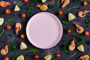 Boş bir pembe plaka karanlık dokulu arka plan ortasında yatıyor. Çevresinde limon, maydanoz, biber, domates ve karides dağılmış. Üstten, güzel fotoğraflar alay.