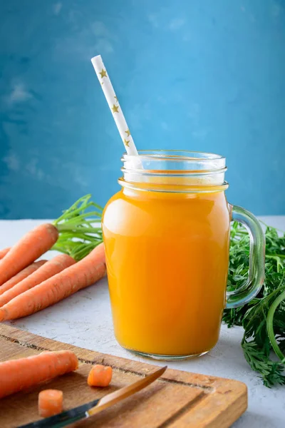 Havuç suyu ve sebze alışılmadık bir mavi arka plan üzerinde güzel kompozisyon bir kavanoz ile. Yararlı veggie içki. Lezzetli kahvaltı.