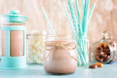 Kakao bir sicim ip ile sargılı bir kavanoza. Arka plan, mavi bir cezve, şekerleme ve kokteyl tüplerde turkuaz: bulanık. Nazik natürmort.