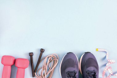 Fitness arka plan metin için yer ile. Sayfanın altından düzeni olan spor spor ayakkabı, atlama ipi, kırmızı dumbell ve bir ölçüm bandı.