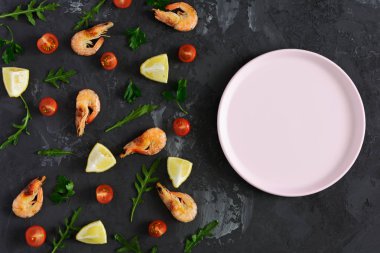 Karanlık dokulu bir arka plan üzerinde boş bir pembe plaka vardır. Dağınık ürünleri kenarından. Karides, limon ve Yeşiller. Kadar alay et. Düşük anahtar içinde renkli fotoğraf.