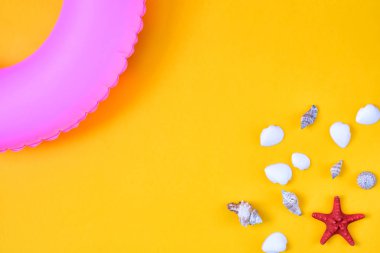 Parlak yaz arka plan, deniz kabuğu, bir deniz yıldızı ve köşedeki şişme bir pembe daire. Parlak sarı düzeni. Üst fotoğraf.