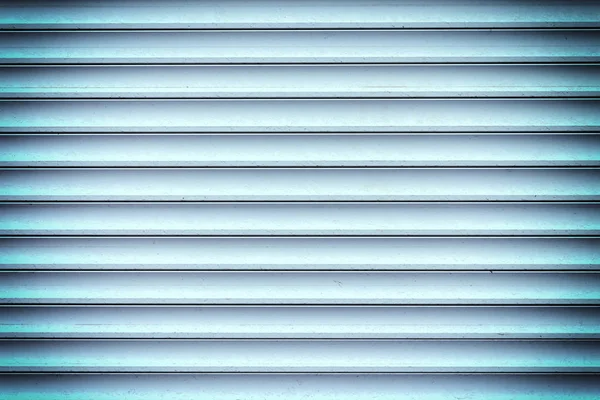 Eine Wand aus glatten Lamellen. Hintergrund aus blauen horizontalen Balken. Foto mit Vignette. — Stockfoto