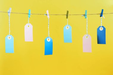 İple buruşuk renkli clothespins, onlar puffs içinde sıkı tutun. Bir yazıt, yukarı alay etmek için bir yer. Sarı bir arka plan resmi.