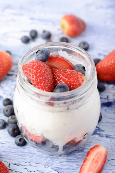 Çilek ve yaban mersini ile bir kavanoza yoğurt. Doğal süt tatlı yakın çekim.