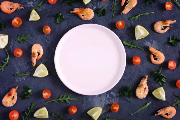 Dokulu bir arka plan üzerinde boş bir pembe levha, gıda dağılmış. Karides, limon ve Yeşiller. Yukarı alay, metin için boşluk. Düşük anahtar içinde renkli fotoğraf.