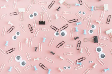 Neşeli desenle parlak pembe arka plan üzerinde dağınık okul malzemeleri.