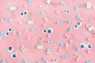 Dağınık ileti örneği ile güzel bir fotoğraf. Komik suratlar kukla gözleri olan. Klipleri, büro düğmeleri ve yıldız bir karmaşa soluk pembe bir arka plan üzerinde.