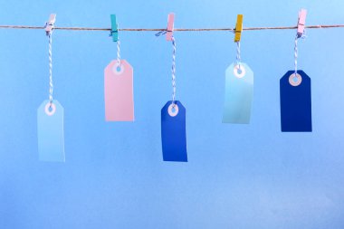 Mavi arka plan fotoğrafı etiketlere. Çok renkli boş etiketleri clothespins ile tutturulmuş ip dayan. Parlak düzen, alay etmek yukarıya.