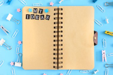 Üst dağınık ileti örneği ile güzel bir fotoğraf. Not defterini springs kahverengi yaprakları ile açın. Yazıt benim fikir. Klipleri, büro düğmeleri ve yıldız bir karmaşa mavi bir arka plan üzerinde.