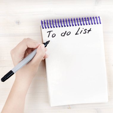 A to-do list in a notepad on spirals. Place for text. The left-hander is holding a marker. Mock up. clipart