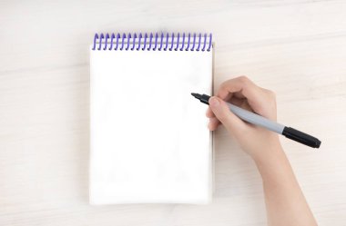 A to-do list in a notepad on spirals. Empty Place for text. A girl's hand holds a marker. Mock up. clipart