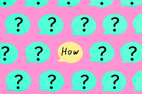 Turquoise stickers with question marks on a pink background. In the center of the yellow sticker with the question HOW. Beautiful bright photo from the top.