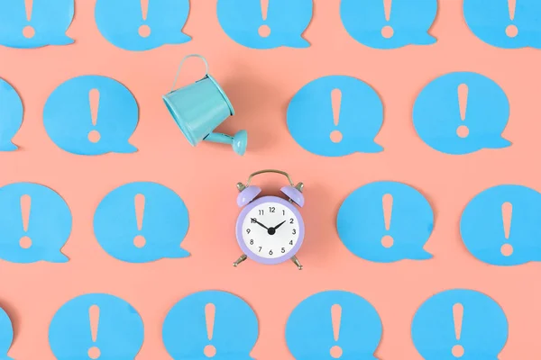 On a pink background, many blue stickers with exclamation marks are pasted. Among them there is a blue watering can and a small alarm clock. An unusual concept, attention to leakage time.