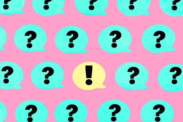 The photo, turquoise stickers with question marks on a pink background. In the center is a yellow sticker with an exclamation point. Beautiful bright pattern.