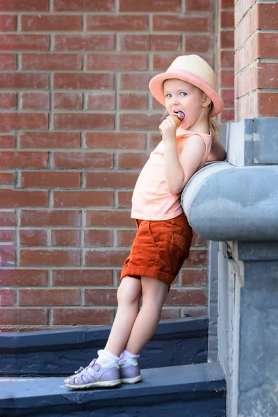 Little Girl Hat Red Shorts Stands Leaning Wall Child Eating — Stock Photo, Image