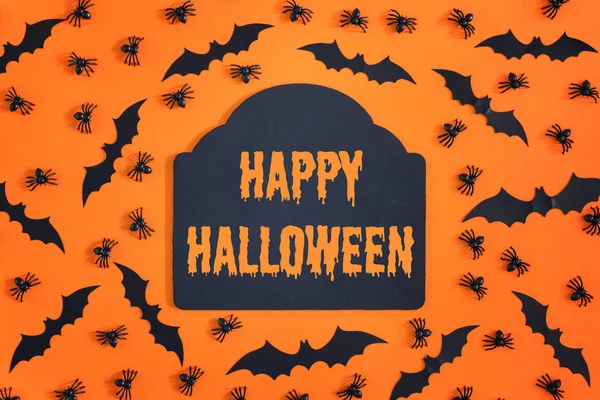 Turuncu arka ortasında bir yazıt ile siyah bir plak mutlu Cadılar Bayramı olduğunu. Dekoratif yarasalar ve örümcekler çevresinde. Korkunç bir tatil için alışılmadık bir fotoğraf.