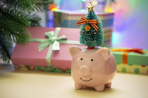Bir Noel ağacı ile küçük seramik piggy banka. Planda bir bulanıklık bir yılbaşı garland ve hediye. Yeni yıl 2019 sembolü. Noel kartı.