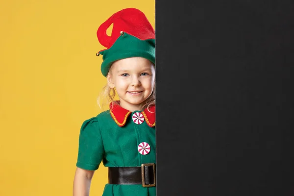小女孩在圣诞节精灵服装站在附近的文本黄色背景 — 图库照片