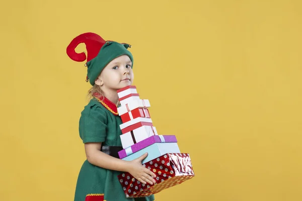 小女孩在圣诞节精灵服装与礼物黄色背景 — 图库照片