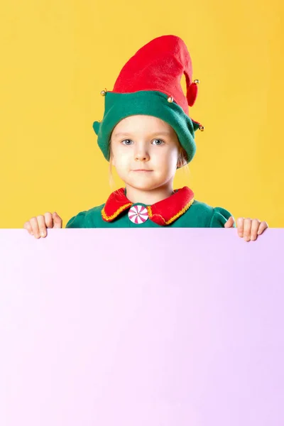 小女孩在圣诞节精灵服装站在黄色背景文本的地方 — 图库照片