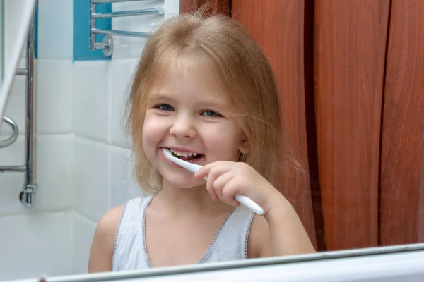 little girl with blond hair brushing her teeth