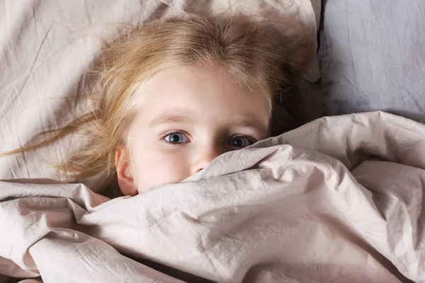 金发碧眼的小女孩躺在家里的床上 — 图库照片