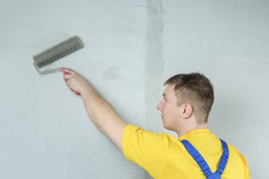 Ev ressamı duvarları harçla kaplar. Tamirci bir silindir ile çalışır.