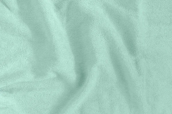 A textura de uma toalha terry. Têxteis verdes amassados desigualmente dispostos. Fundo em branco . — Fotografia de Stock