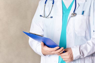 Yakın çekim, beyaz tıbbi paltolu kırpılmış bir adam. Doktor hastanın kartını tutar..