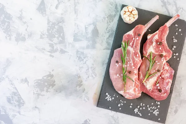 Два куска сырого мяса на резке доска с розмарином — стоковое фото