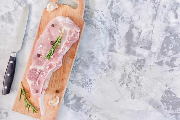 Копируйте пространство на каменном фоне. Мясо стейк с перцем, чесноком и розмарином. Кусок сырой свинины лежит на деревянной доске . — стоковое фото
