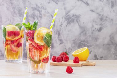 Çilek ve nane ile limonata. Kesme tahtası yanında malzemeler vardır. Uzun bir cam yaz serinletici içecek.