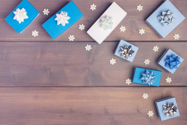 Composição de Natal em semicírculo em fundo de madeira. Caixas de presente brancas e azuis decoradas com arcos e flocos de neve decorativos . — Fotografia de Stock