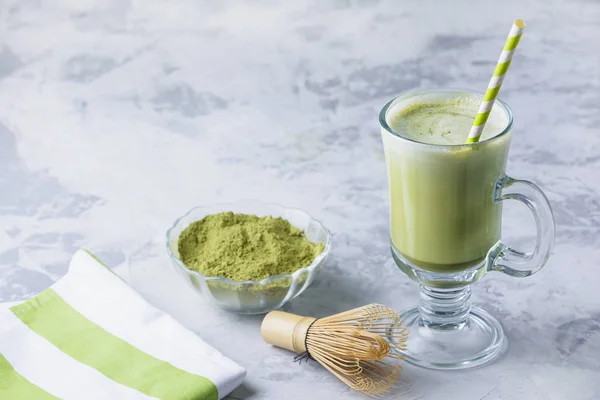 Matcha yeşil çay latte. Şeffaf bir bardak, yeşil çay tozu ve bambu çırpıcı sağlıklı bir içecek. Metin için yer içeren fotoğraf, kopyalama alanı