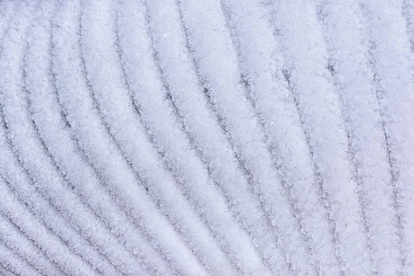 Sneeuw oppervlak met sneeuw textuur close-up. Abstracte achtergrond met ijzige gebogen lijnen. De basis voor de site of de lay-out — Stockfoto