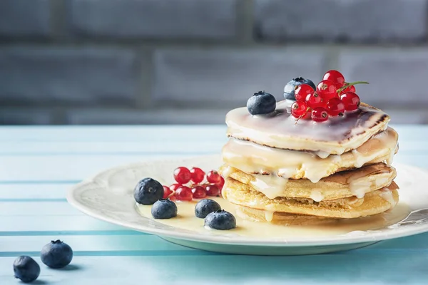 Fresh pancakes are sprinkled with condensed milk and decorated with blueberries and currants. Tasty and healthy dessert close-up. Bright photo — Stock Photo, Image