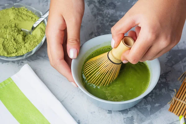 Menina mexe matcha chá verde um batedor de bambu. O processo de fazer chá close-up — Fotografia de Stock