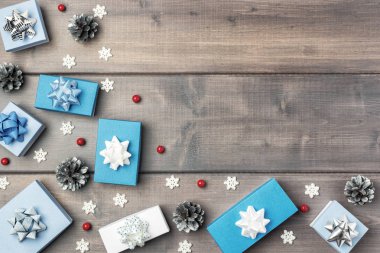 Noel kompozisyonu küçük hediye kutuları, koniler, kırmızı böğürtlenler ve tahta arka planda dekoratif kar taneleri. 