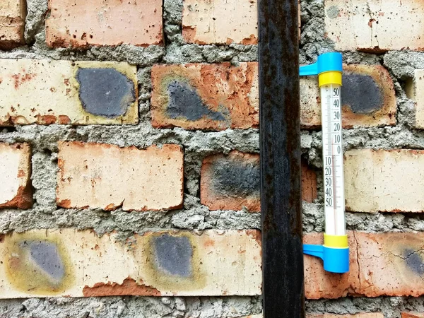 old brick wall with thermometer on it temperature