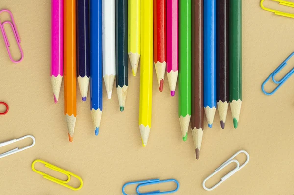 Montones de lápices de colores y clips de papel sobre un fondo beige agradable —  Fotos de Stock