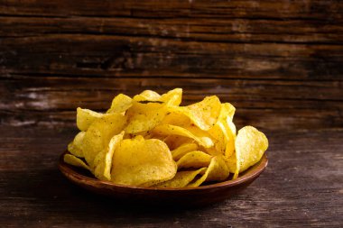 Gevrek tuzlu lezzetli patates cipsi karanlık ahşap plaka 