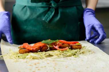 Kimliği belirsiz Şef soslu, falafel rulo hazırlanıyor turşu ve