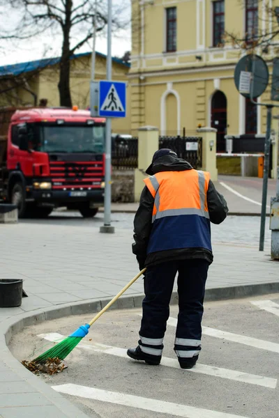 Працівник прибиральної компанії збирає, прибирає міську вулицю з б — стокове фото
