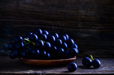 Koyu ahşap arka plan üzerinde plaka tatlı Olgun üzüm