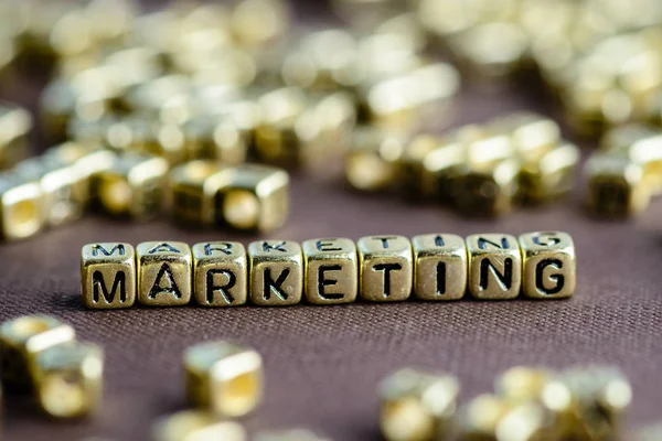 Word Marketing gemaakt van kleine gouden letters op de bruin backg — Stockfoto