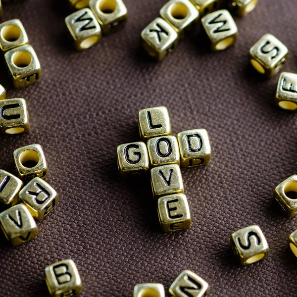 Phrase LOVE GOD made from small golden letters on the brown back