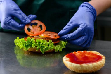 Bilinmeyen cook vejetaryen burger koyarak hazırlamak dilimlenmiş domates üzerinde 