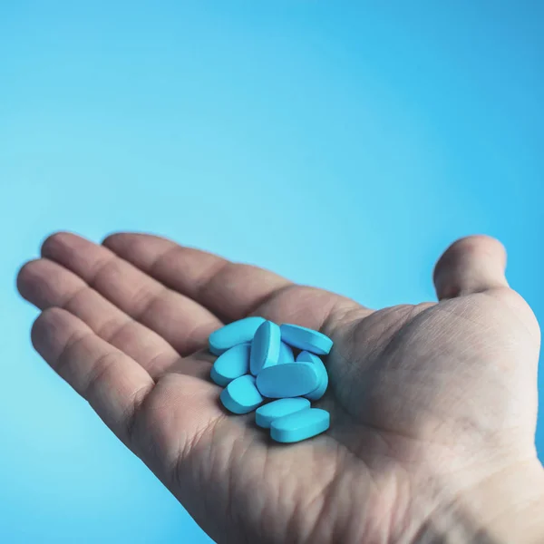 Blå piller i en patienter händer på blå bakgrund. Ta hand om den — Stockfoto